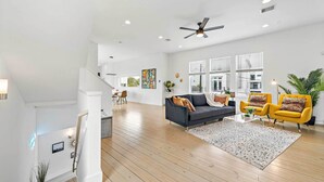 A spacious living area with a dark sofa, yellow armchairs, and a coffee table. - Downtown Houston Townhome w/ Balcony + Yard! (Houston)