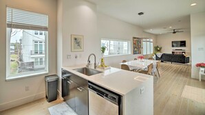 A modern kitchen with a dishwasher, sink, and a dining area with a table and chairs. - Downtown Houston Townhome w/ Balcony + Yard! (Houston)
