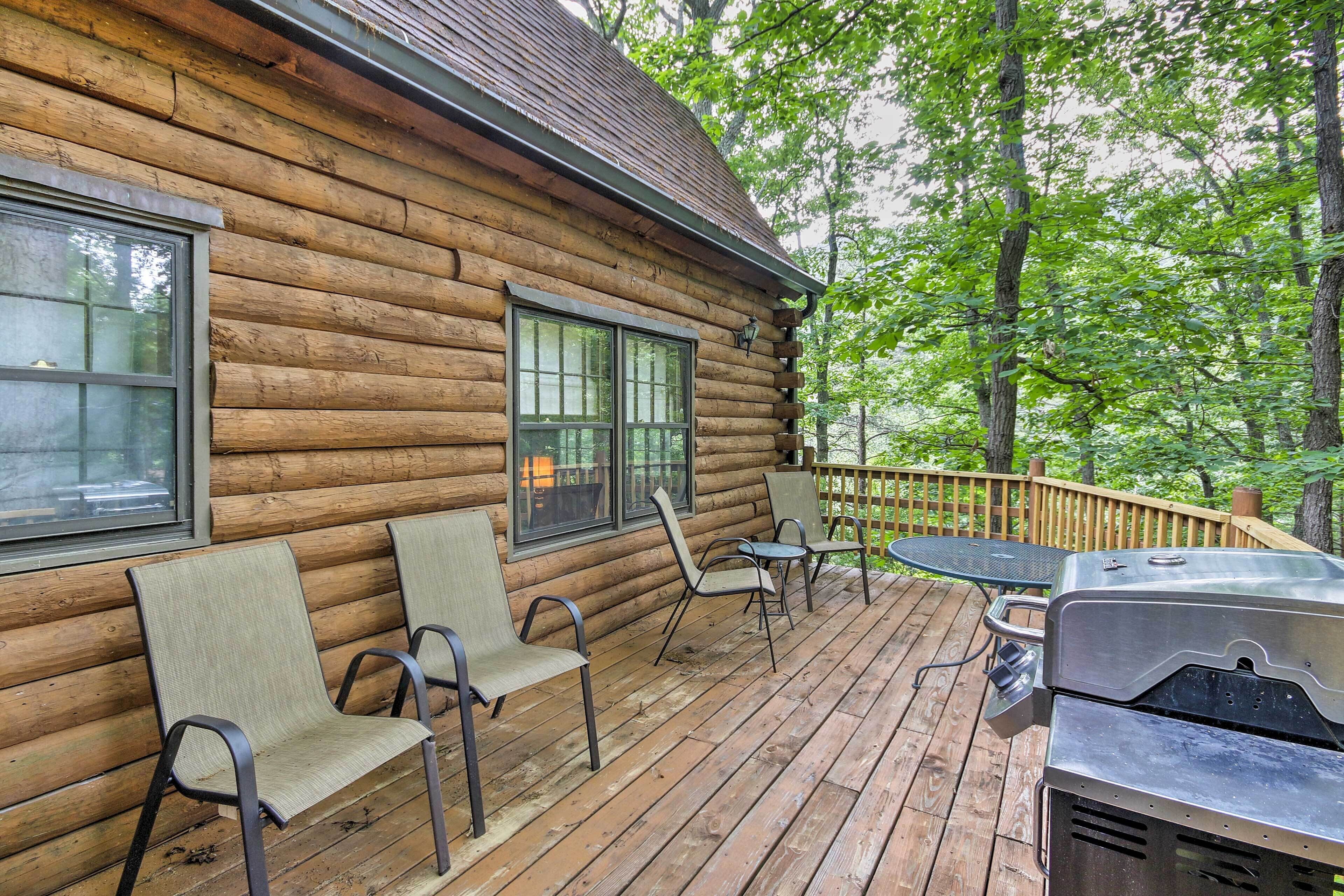 Eine Blockhütte mit einer Terrasse, die Sitzgelegenheiten und einen Grill bietet.