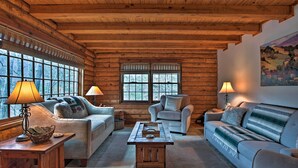 A cozy log cabin interior with two sofas, a coffee table, and lamps.
