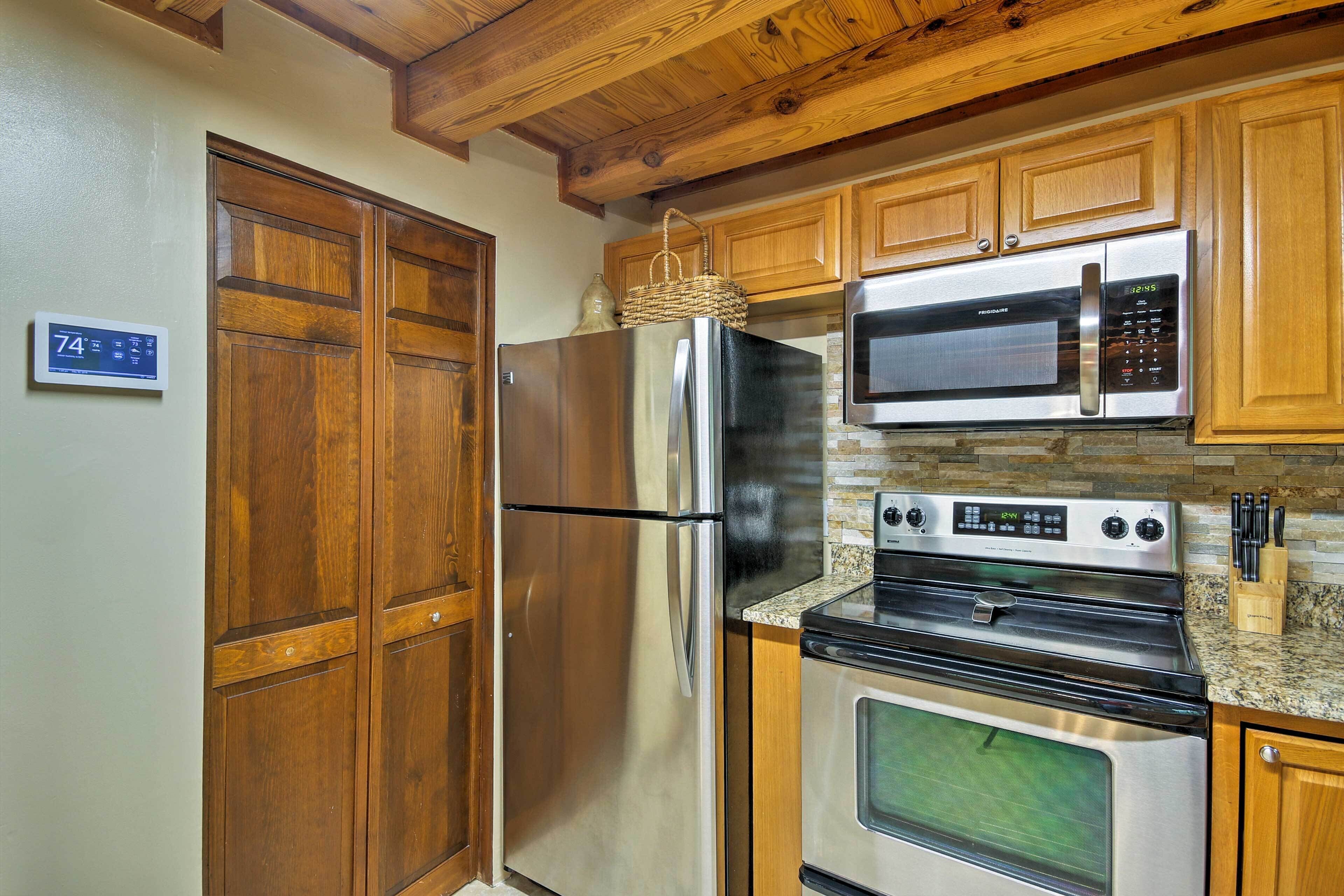 Eine Küche mit Holzschränken, einem Edelstahlkühlschrank, einer Mikrowelle und einem Backofen.