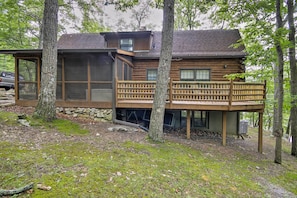 A log cabin with a balcony, surrounded by trees.