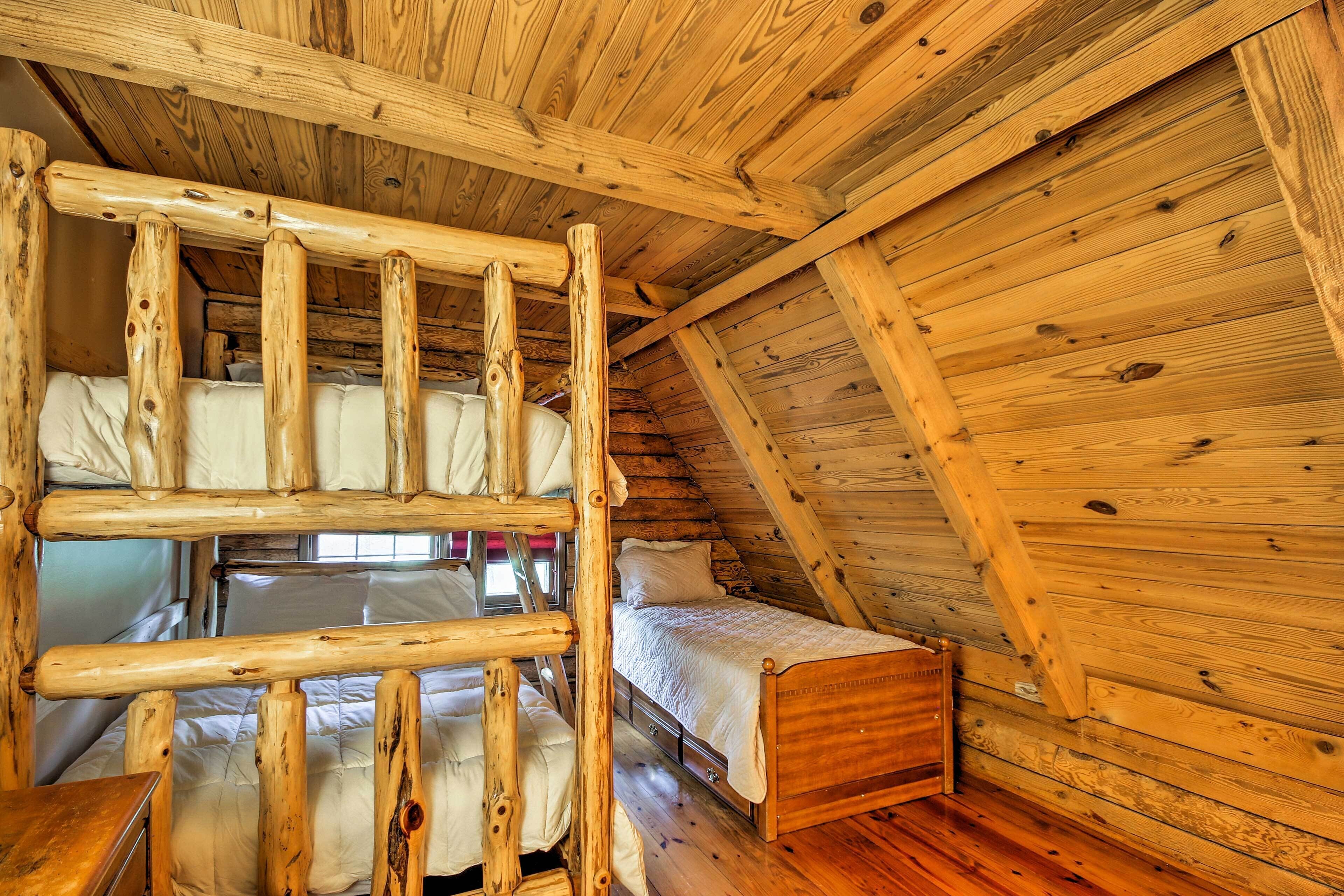 A wooden cabin with a loft bed, a lower bunk bed, and a single bed.