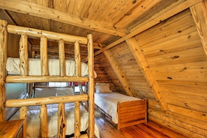 A wooden cabin with a loft bed, a lower bunk bed, and a single bed. - Family-friendly Massanutten Log Home w/ Views! (McGaheysville)