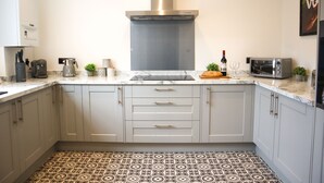 A modern kitchen with grey cabinets, a stainless steel range hood, a built-in microwave, and a patterned floor.