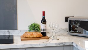 A kitchen counter with a loaf of bread, a bottle of wine, and two wine glasses.
