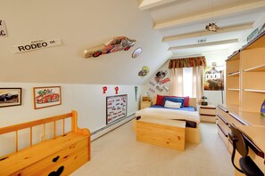 Ein Kinderzimmer mit einem Bett, einer hölzernen Bank, einer Wand mit Rennwagen-Aufklebern und einem Regal mit einem Spielzeugauto.