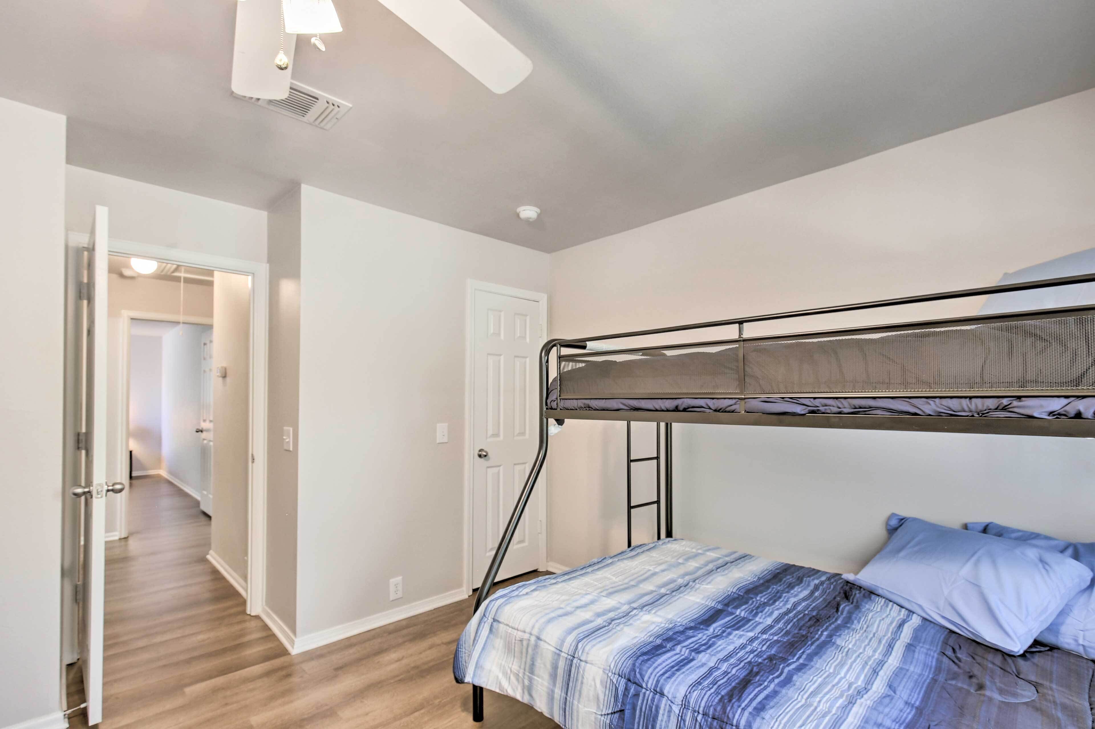 A bedroom with a bunk bed, a door leading to another room, and a hallway.
