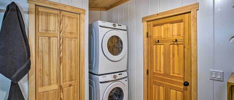 A laundry room with wooden cabinets and stacked washing machines.