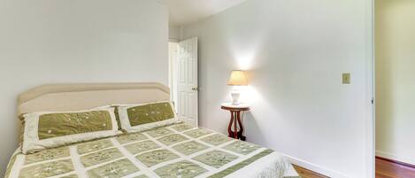 Un dormitorio con cama, una mesita de noche con lámpara y una puerta.