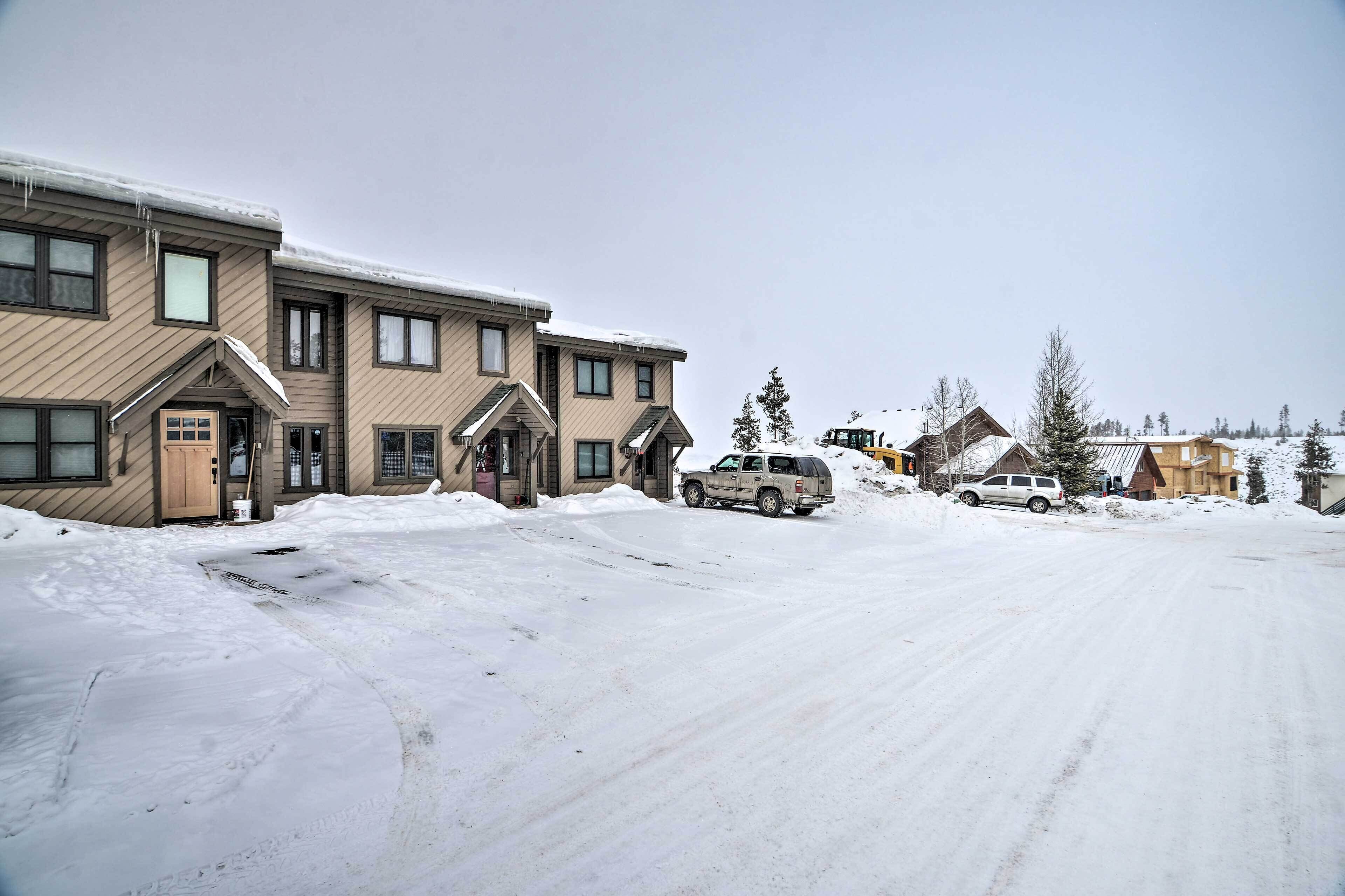 A residential area with a two-story building, a driveway, and parked vehicles.
