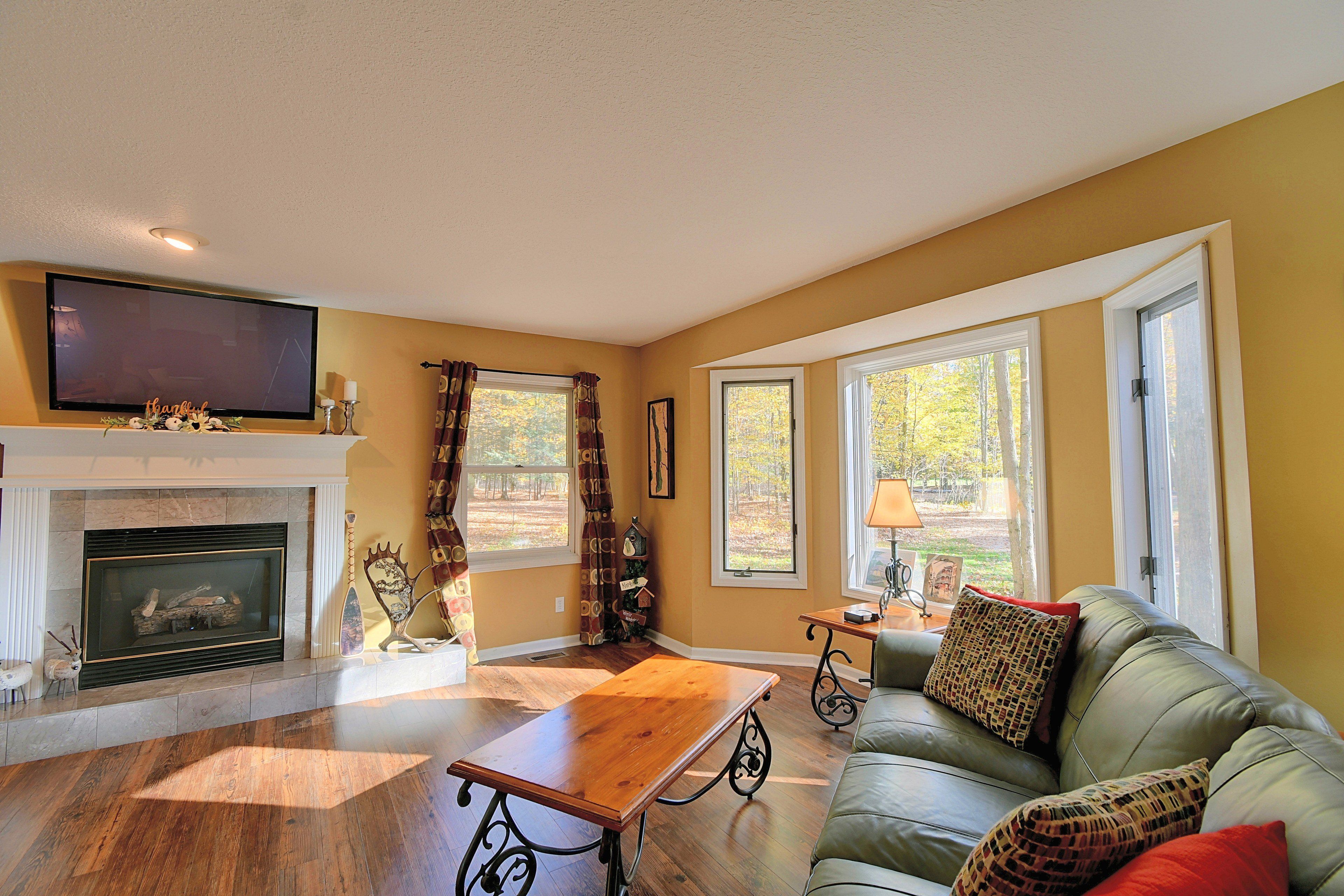 A living room with a fireplace, a sofa, a coffee table, and large windows.
