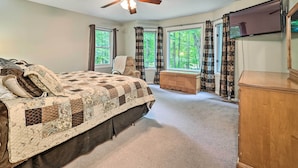 A bedroom with a large bed, a ceiling fan, a TV mounted on the wall, and a window with curtains. - Bellaire Ski Escape ~ 1 Mile to Schuss Mountain! (Bellaire)