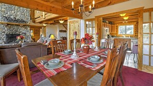 A wooden dining table set for six with a stone fireplace in the background.
