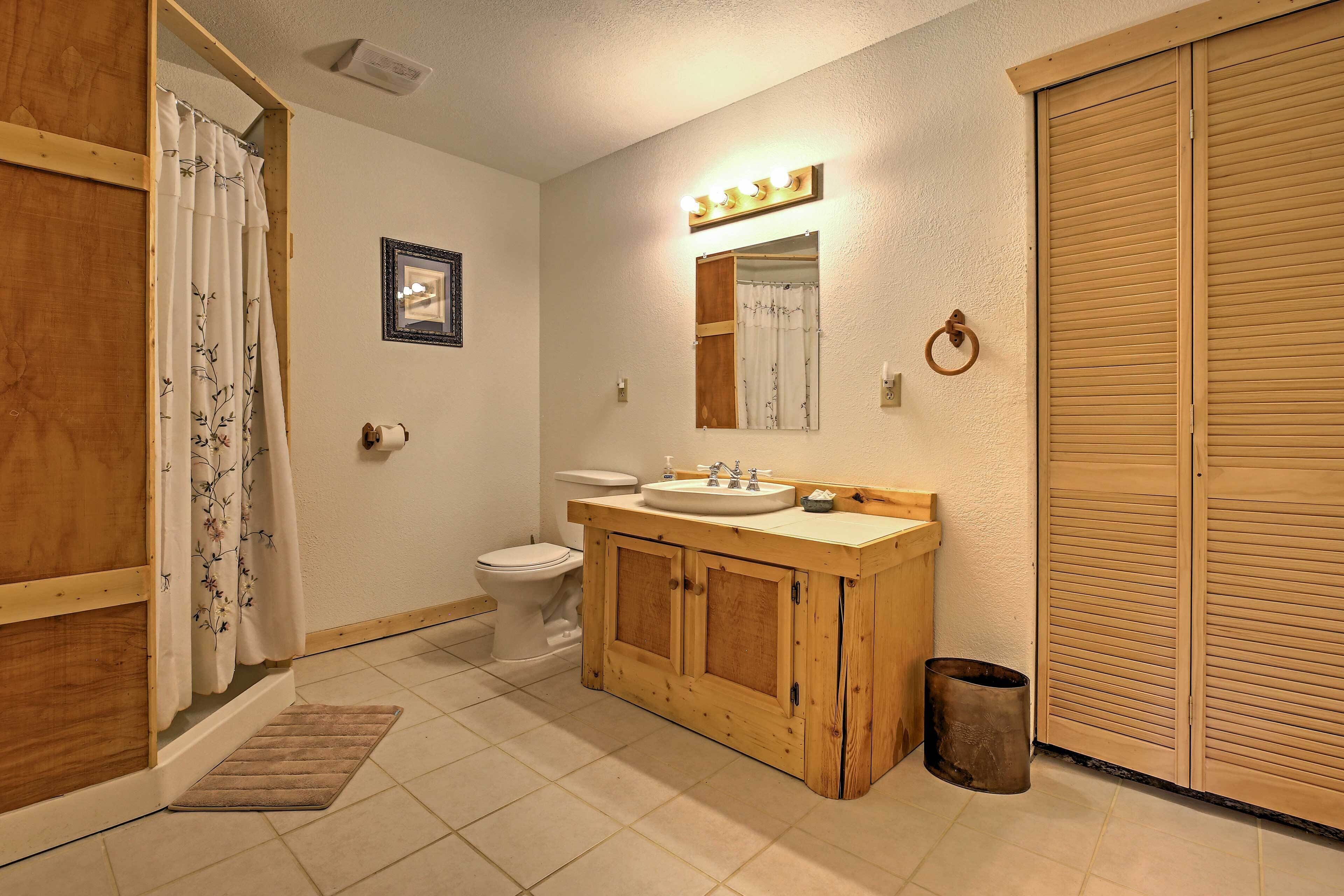 A bathroom with a wooden vanity, a toilet, and a shower curtain.