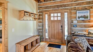 A rustic cabin interior with a wooden bench, a door with glass panels, and a framed picture on the wall. - Hot Tub & Fire Pit: Getaway Near Nantahala Gorge! (Franklin)
