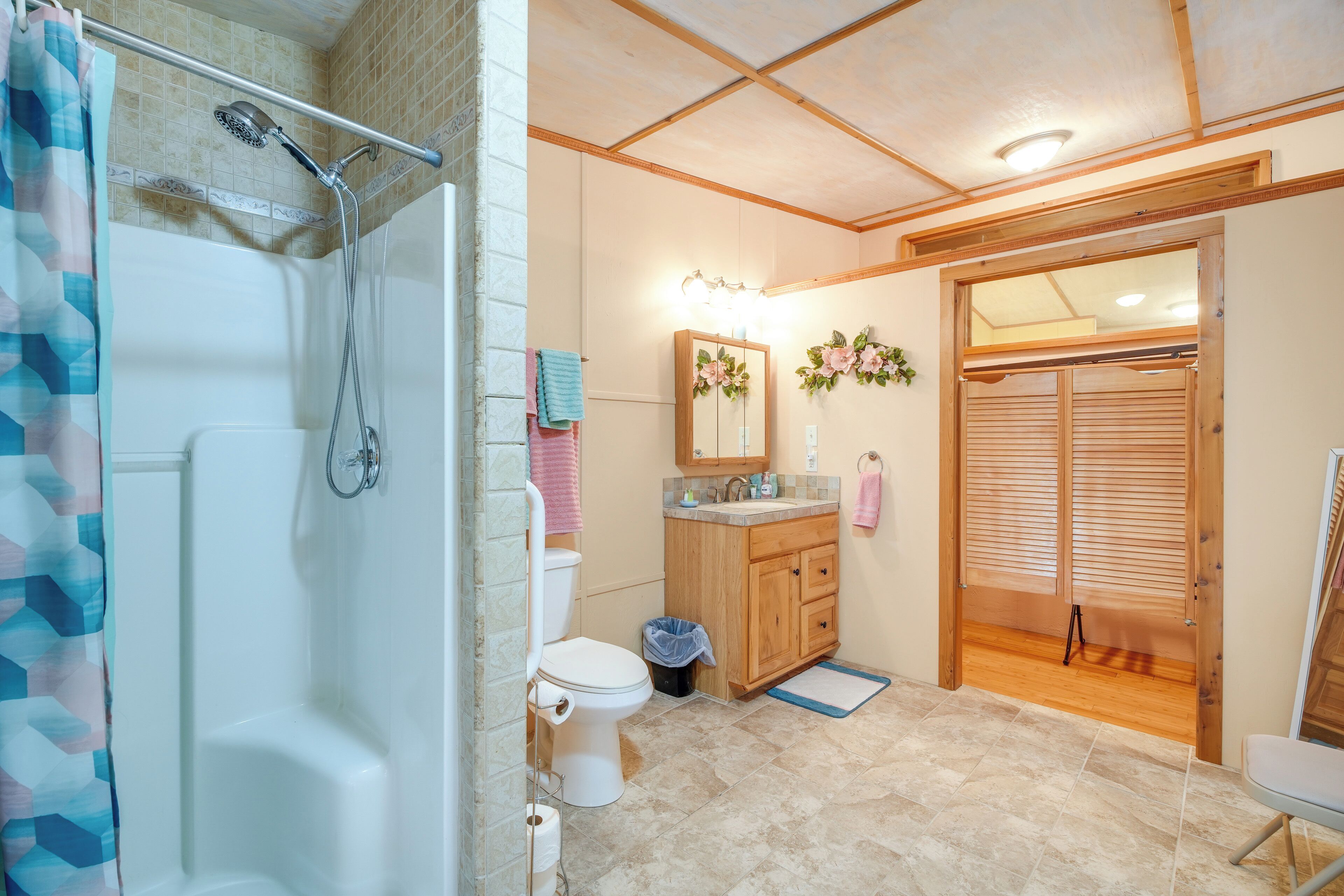 Une salle de bain équipée d’une douche, de toilettes, d’un lavabo et d’une porte en bois donnant sur une autre pièce.