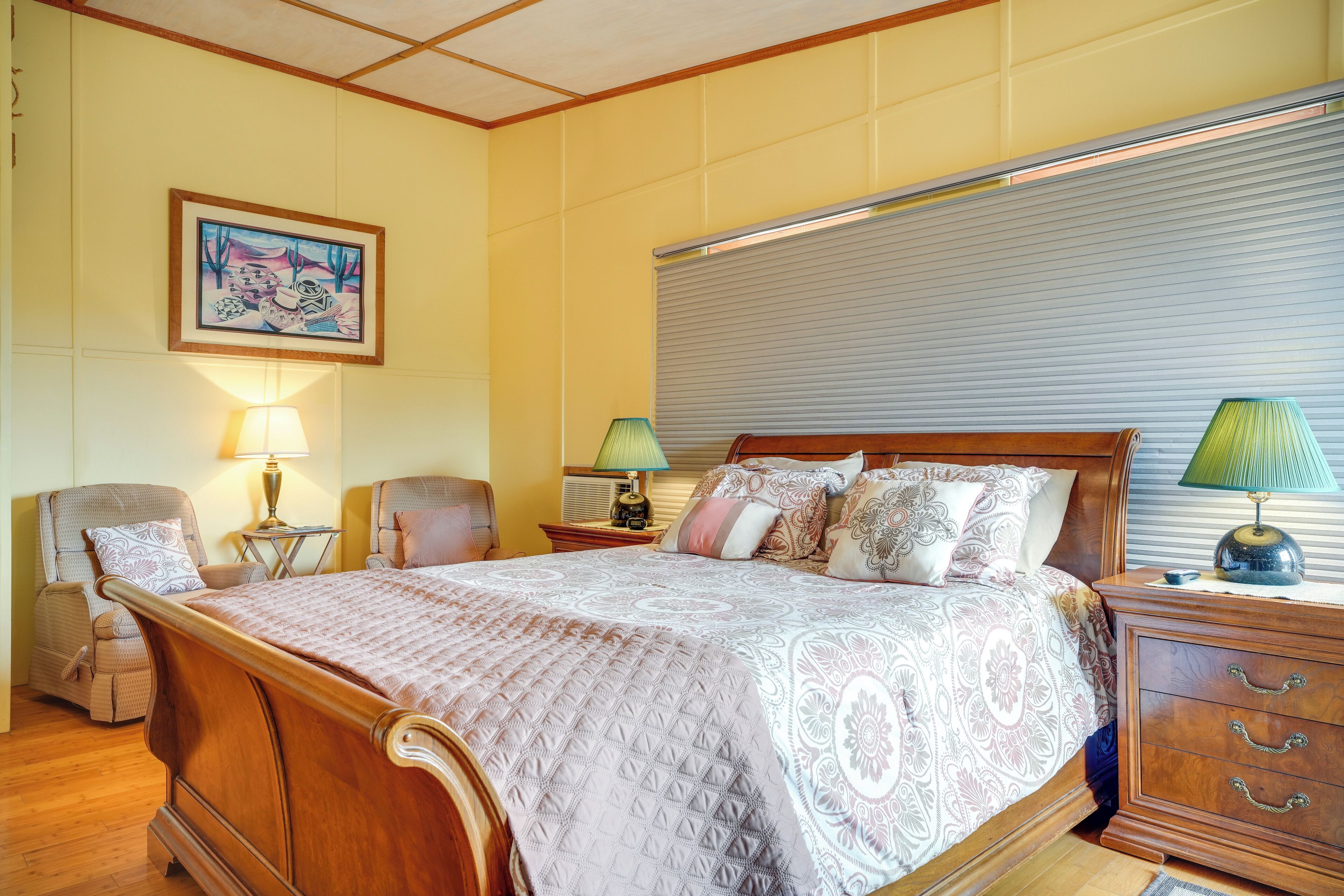 Une chambre à coucher avec un grand lit, deux tables de chevet, une chaise, une lampe et un tableau au mur.