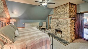 A bedroom with a bed, a ceiling fan, a stone fireplace, and a view of the outdoors. - Historic Virginia Wine Country Villa w/ Pool, Yard (Linden)