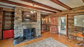 A rustic interior with a stone fireplace, wooden beams, and a red cabinet. - Historic Virginia Wine Country Villa w/ Pool, Yard (Linden)