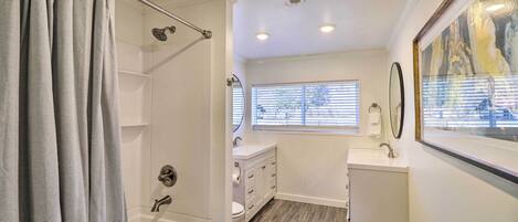 A modern bathroom with a bathtub, shower, and vanity.