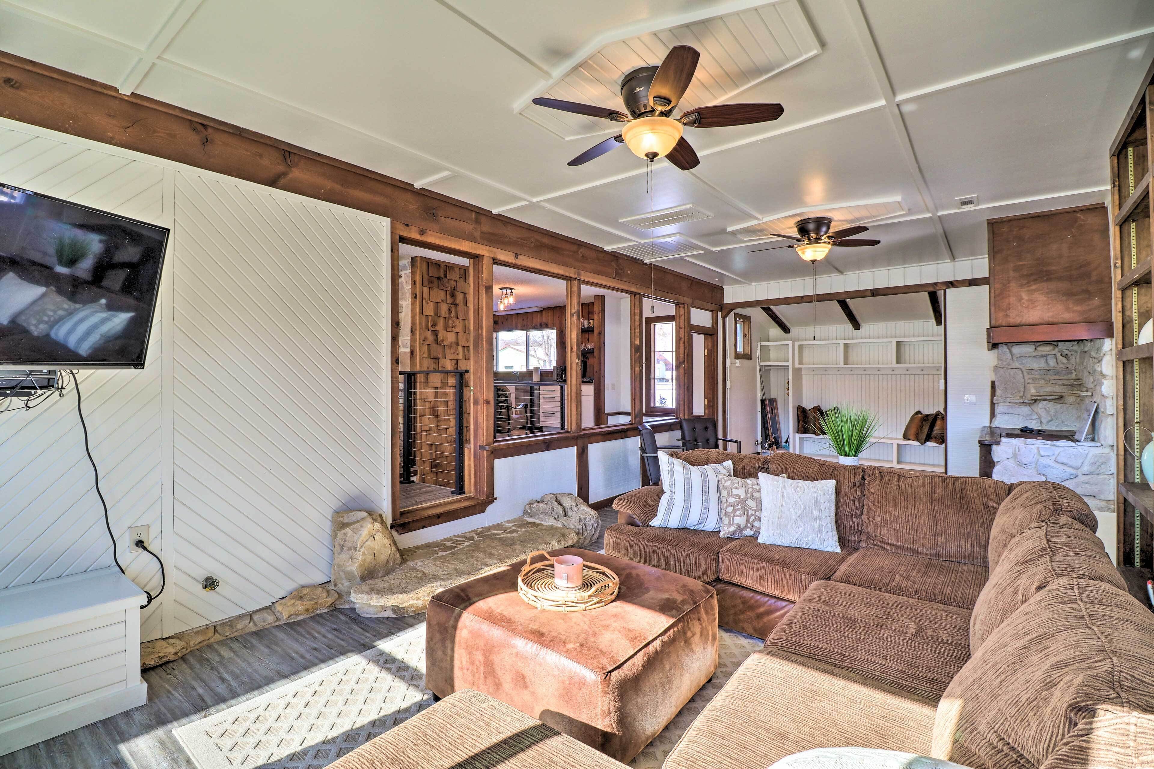 A spacious living area with a large brown sectional sofa, a wooden coffee table, and a ceiling fan.