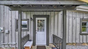 Una casa in legno con una porta bianca, una panchina e un tavolinoino fuori.