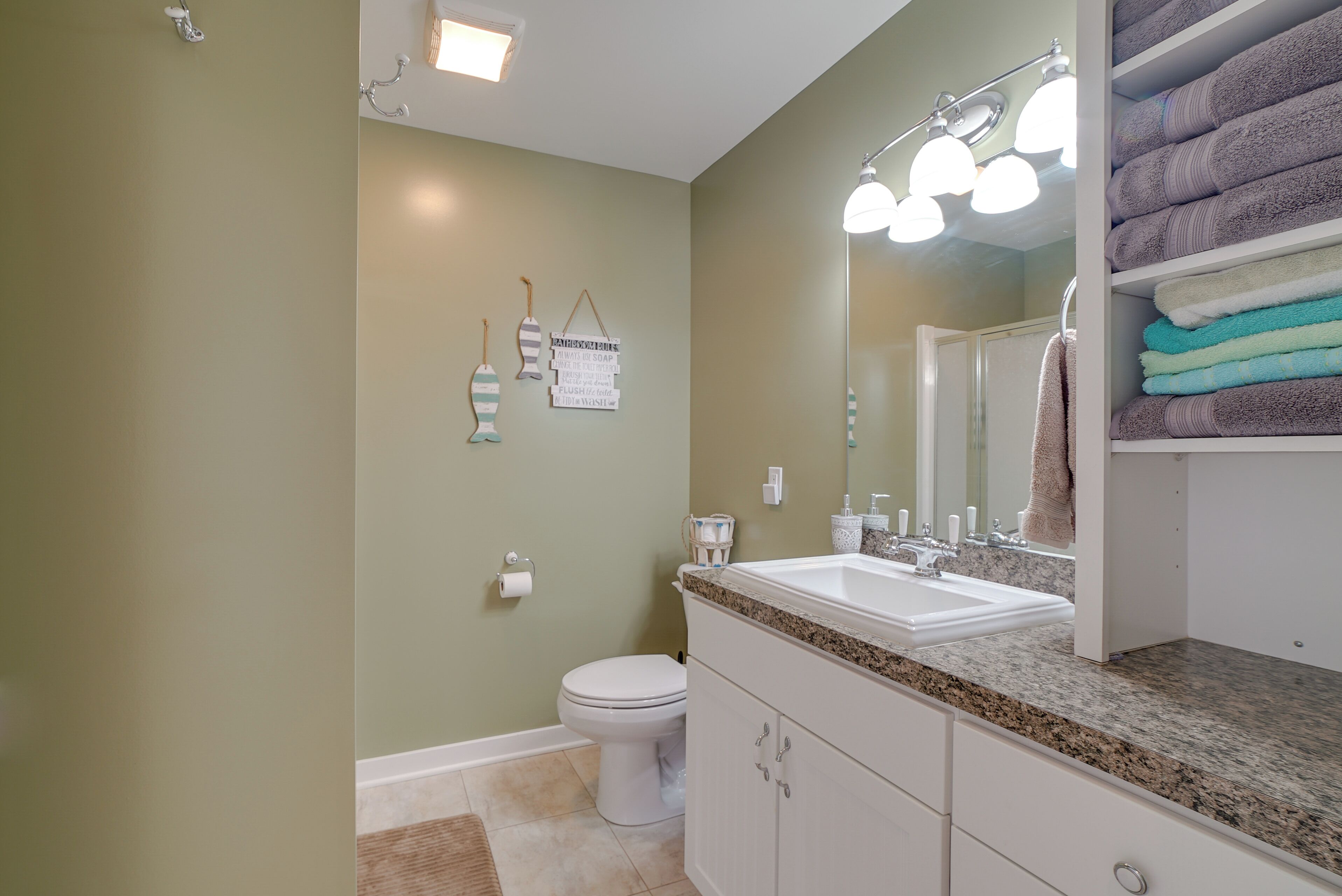 Une salle de bain avec un lavabo blanc, un meuble-lavabo et un porte-serviettes.