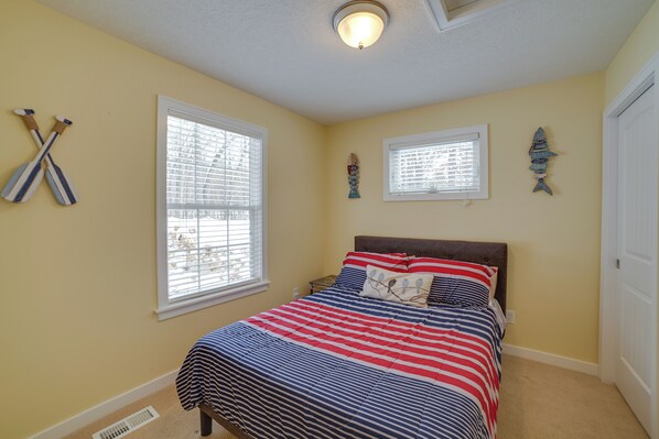 Un dormitorio con cama, dos ventanas y decoración en las paredes.