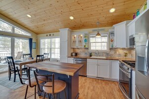 Una cocina amplia con techo de madera, armarios blancos, una isla central y un comedor con sillas.