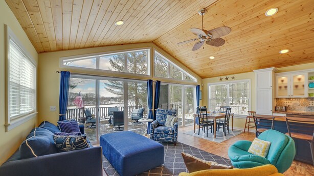 A spacious living area with a high ceiling, large windows, and a cozy seating arrangement. - Fish, Hike & Hunt: Lakeside Newaygo Cottage (Newaygo)
