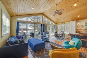 A spacious living area with a high ceiling, large windows, and a cozy seating arrangement. - Fish, Hike & Hunt: Lakeside Newaygo Cottage (Newaygo)