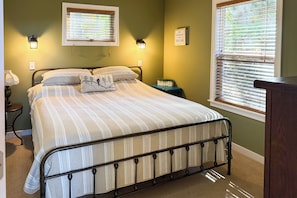 A bedroom with a bed, two wall-mounted lamps, a window with blinds, and a bedside table with a lamp. - Fish, Hike & Hunt: Lakeside Newaygo Cottage (Newaygo)