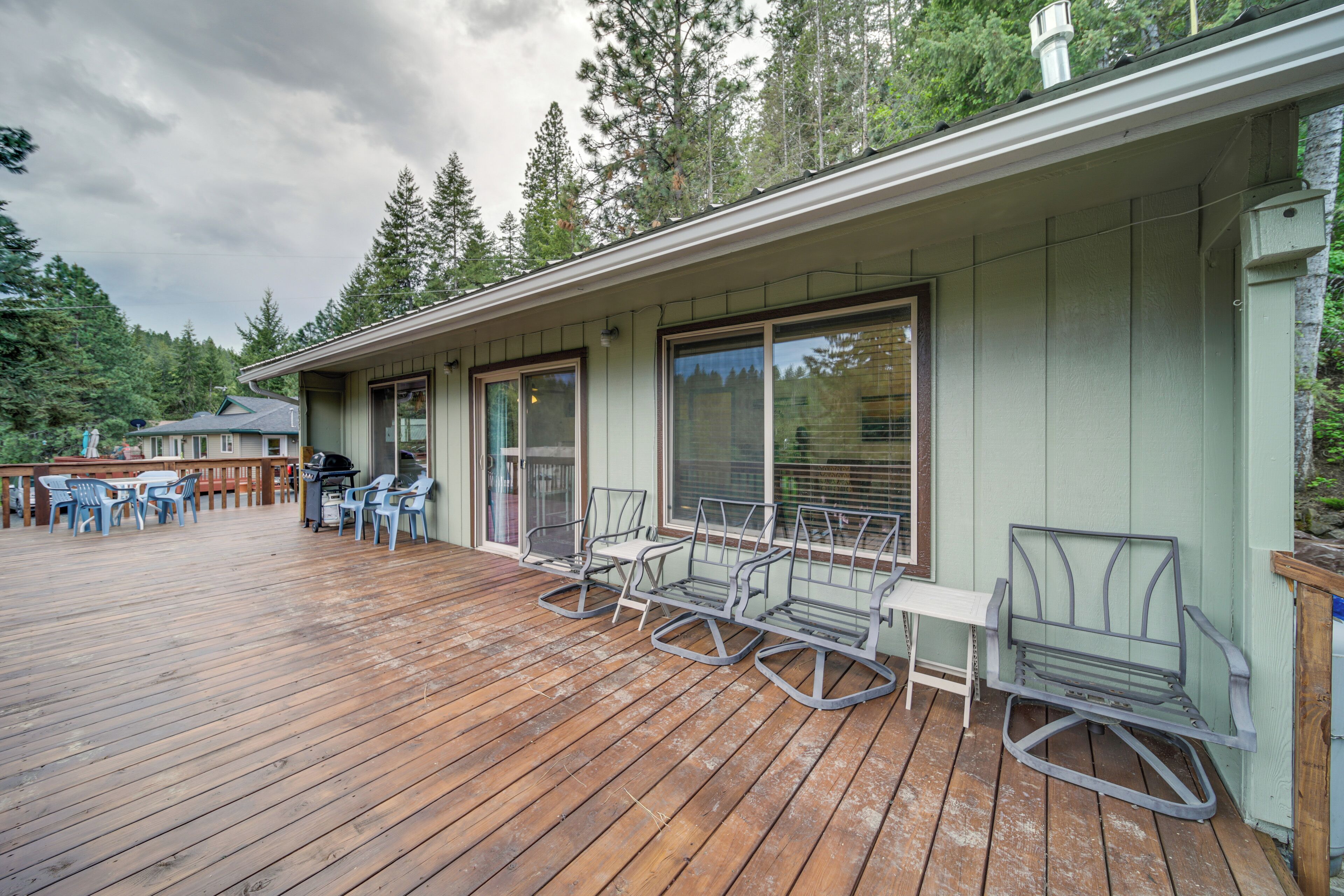 A wooden deck with outdoor furniture, a grill, and a covered patio area.