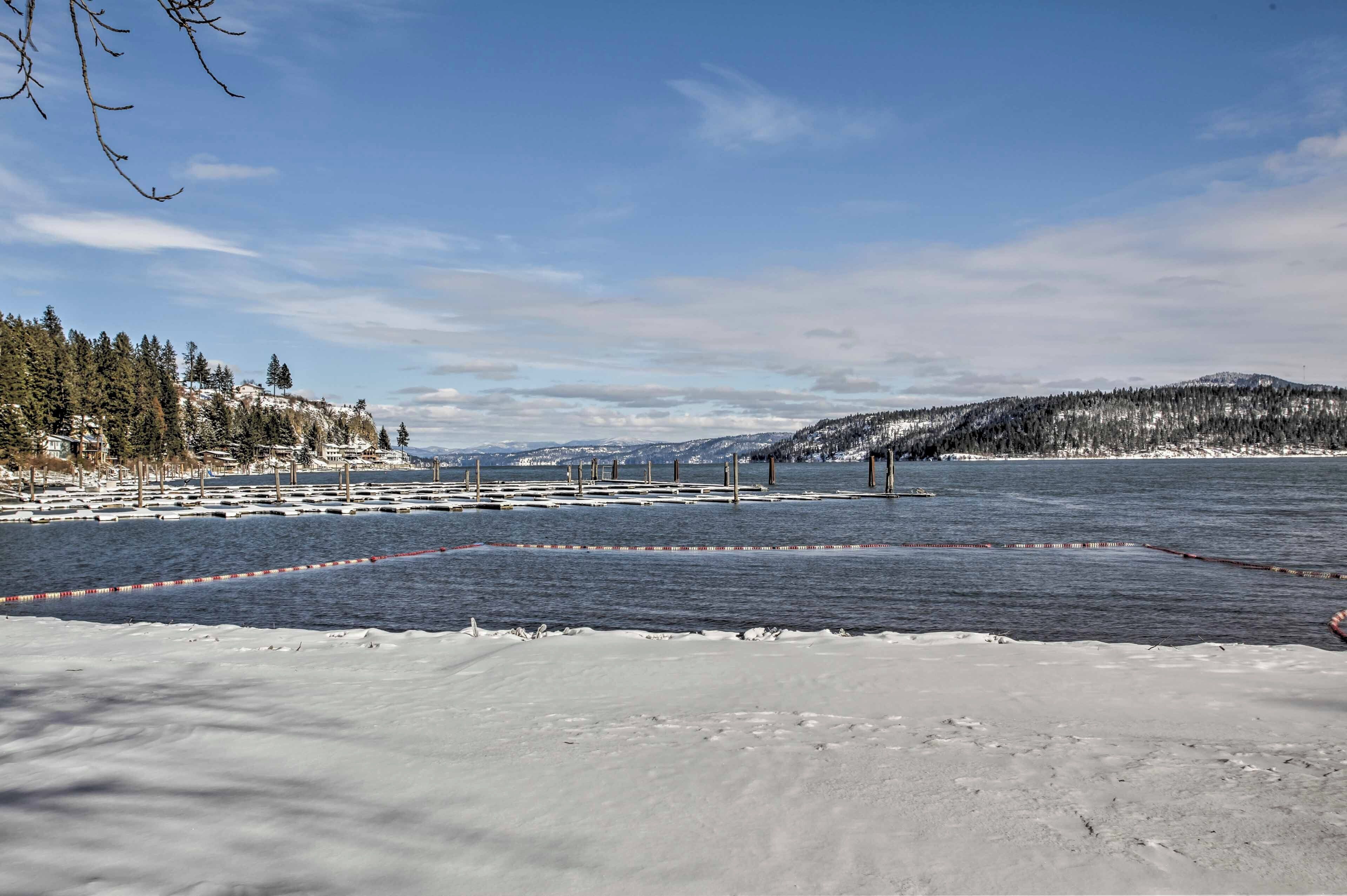 A snowy landscape with a frozen lake, a wooden dock, and a distant mountain range.