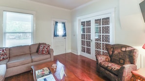 A living room with a brown leather sofa, a patterned armchair, a wooden coffee table, and a ceiling fan. - Harrison Family Home w/ Grill - Near Downtown! (Harrison)