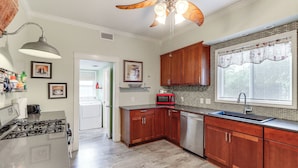 A kitchen with wooden cabinets, a stainless steel sink, a microwave, and a ceiling fan. - Harrison Family Home w/ Grill - Near Downtown! (Harrison)