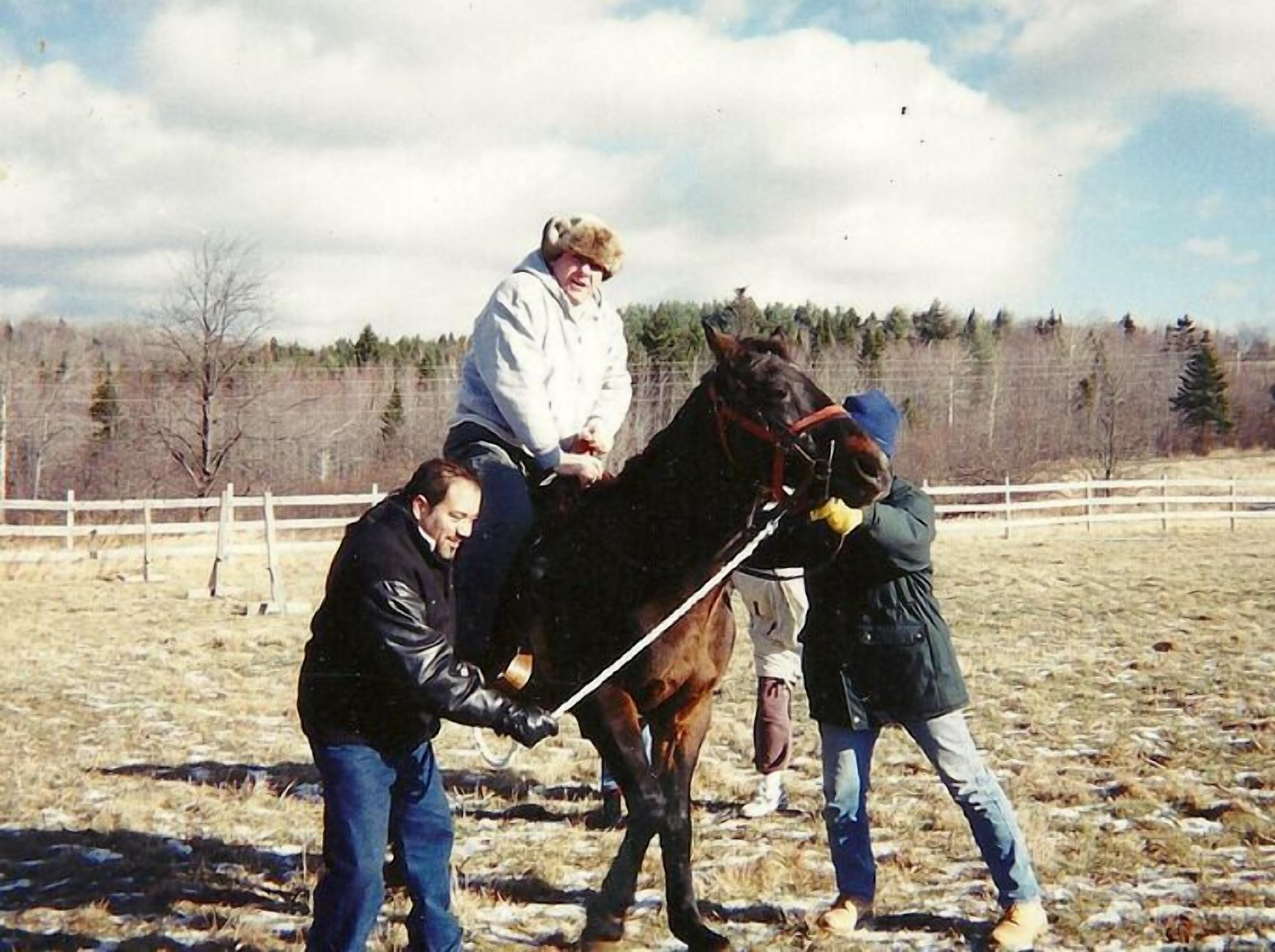 A stable with a horse and two people handling it.