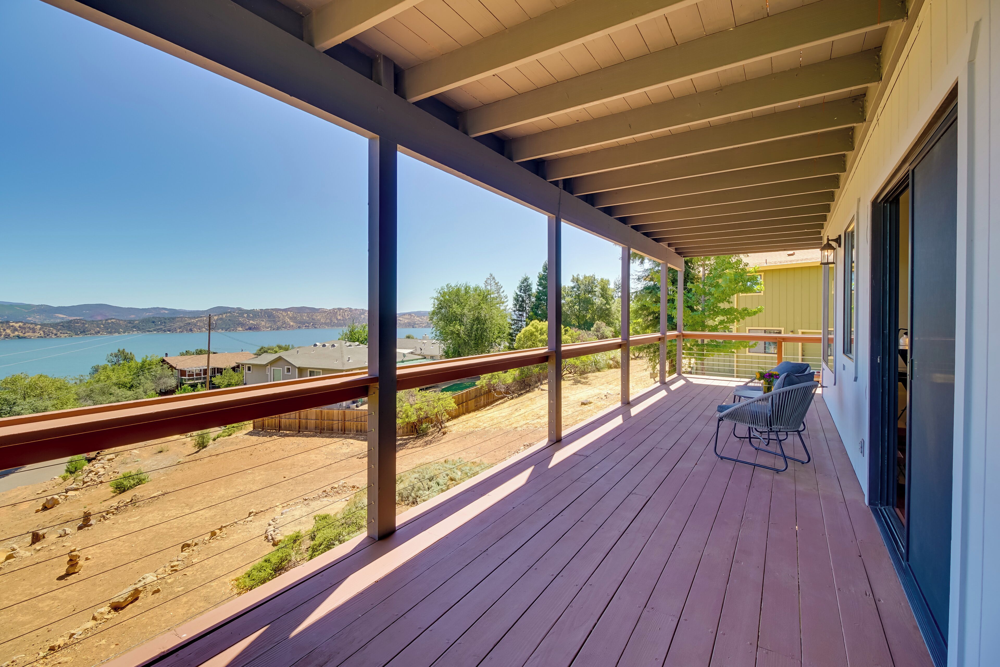 A wooden deck with a railing, a chair, and a table.