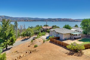 Una casa con patio trasero, zona vallada y vistas a un lago y montañas.