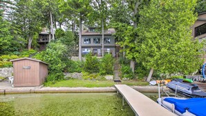 A lakeside property with a dock, a small shed, and a multi-story building surrounded by trees. - Lakefront Plymouth Cottage w/ Private Hot Tub (Plymouth)