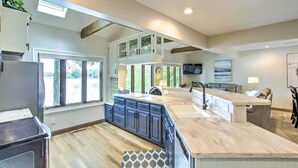A spacious kitchen with a large island, built-in cabinets, and a view to the outdoors. - Lakefront Plymouth Cottage w/ Private Hot Tub (Plymouth)