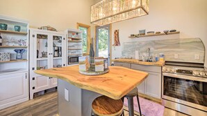 A modern kitchen with a wooden island, stainless steel appliances, and a decorative chandelier. - Contemporary Home w/ Deck & Mountain Views! (Waynesville)