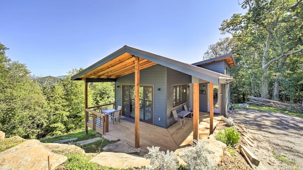 A modern house with a deck, large windows, and a view of a forested area. - Contemporary Home w/ Deck & Mountain Views! (Waynesville)