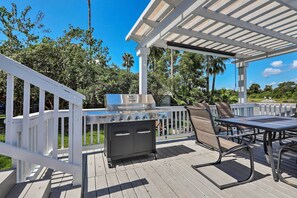 An outdoor deck with a barbecue grill, seating area, and a pergola. - Home on San Jacinto River w/ Pool, Dock & Deck! (Houston)