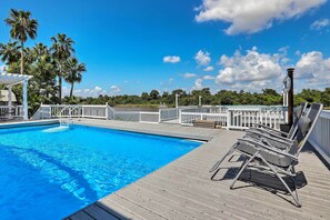 A pool with a wooden deck, lounge chairs, and a lifebuoy. - Home on San Jacinto River w/ Pool, Dock & Deck! (Houston)