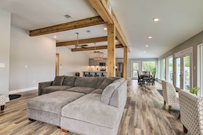 Un amplio espacio de estar con un sofá modular, vigas de madera y una zona de comedor con mesa y sillas.