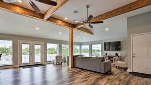A spacious living room with hardwood flooring, a large gray sofa, and a ceiling fan.