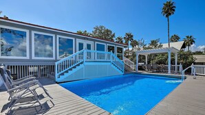 A wooden deck with a swimming pool, a covered seating area, and a building with large windows.