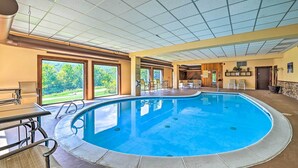 An indoor swimming pool with a view of the outdoors, a reception area, and a seating area with chairs and tables. - Comfortable Dover Apartment: Walk to Mt Snow! (West Dover)